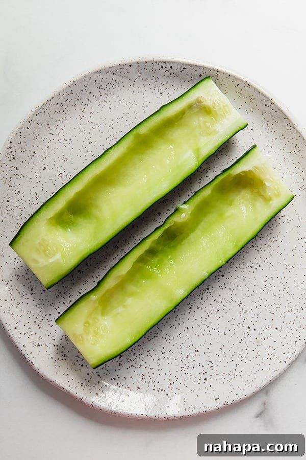 Wholesome Avocado Tuna Cucumber Boats for Clean Eating 4 A cucumber being sliced in half lengthwise, showing the process of preparing it for tuna salad boats.