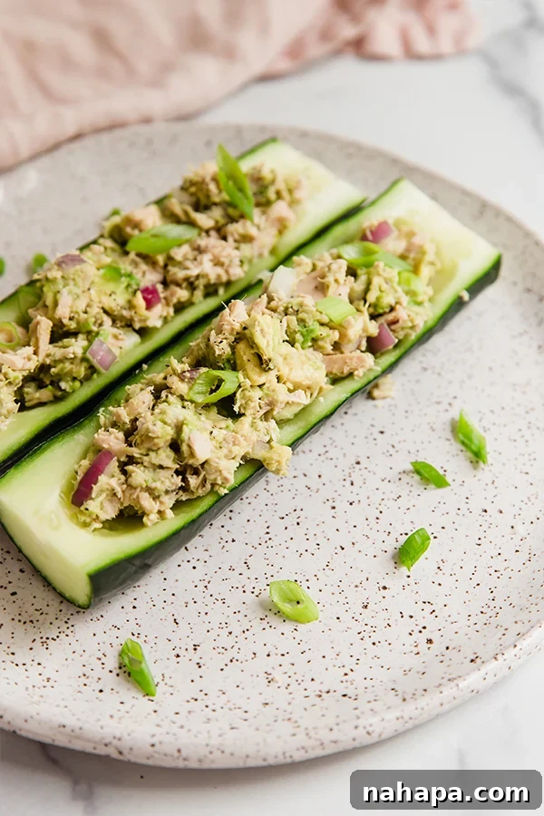 Wholesome Avocado Tuna Cucumber Boats for Clean Eating 6 Five cucumber avocado tuna salad boats arranged neatly on a serving dish, ready to be enjoyed.