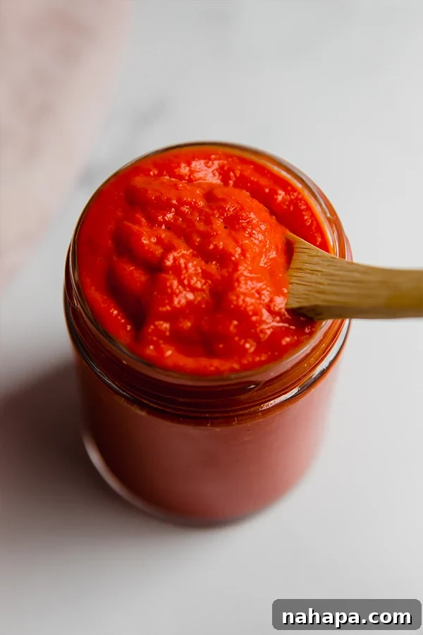 AIP Approved Ketchup 2 A bottle of vibrant red tomato-free AIP ketchup next to fresh carrots and beets