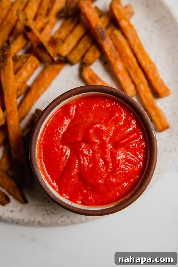 AIP Approved Ketchup 4 Two jars of tomato-free AIP ketchup with a wooden spoon, garnished with fresh carrots and beets.