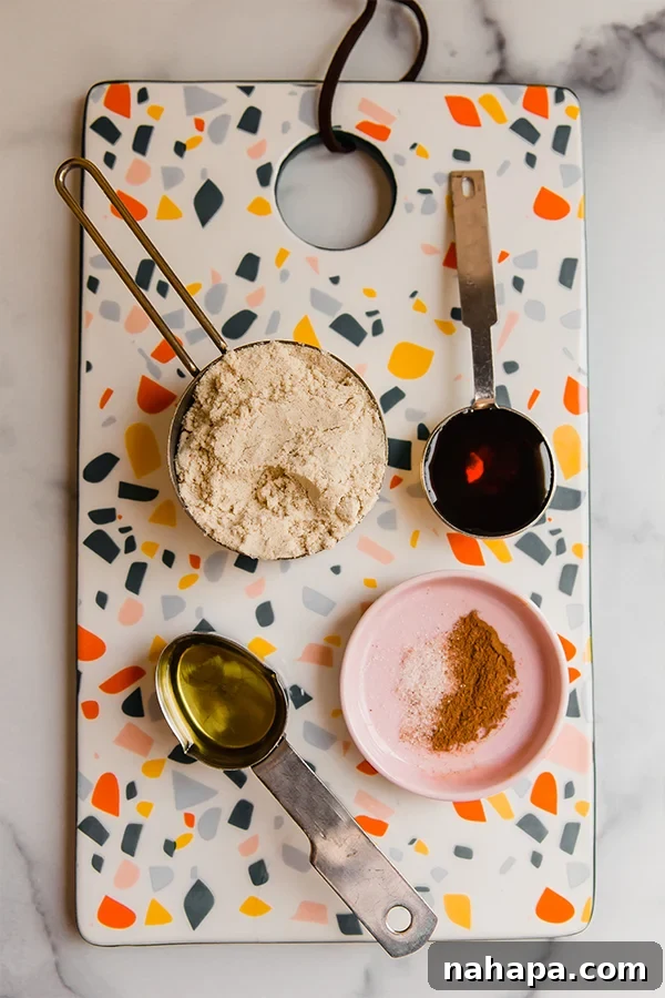 Kendi Kaplan Cevizi Ezmeni Kendin Yap! 3 All ingredients for tigernut butter, including flour, avocado oil, maple syrup, cinnamon, and salt, are meticulously measured and displayed on a vibrant multicolored cutting board.