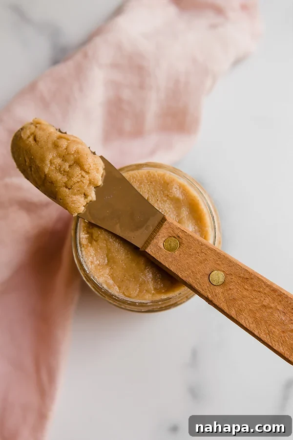 Kendi Kaplan Cevizi Ezmeni Kendin Yap! 4 A glass jar filled with luscious homemade tigernut butter, accompanied by a butter knife, hinting at its smooth, spreadable quality.