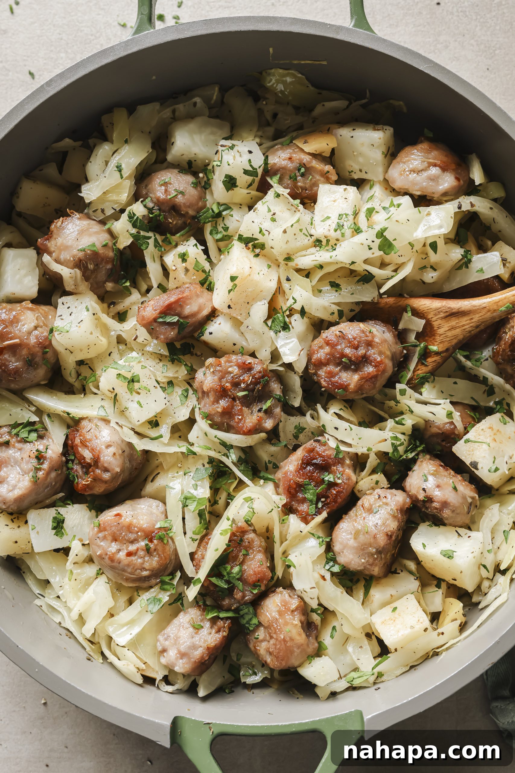 A vibrant, close-up shot of the cooked cabbage and sausage breakfast skillet in a cast-iron pan, showcasing a medley of ingredients.