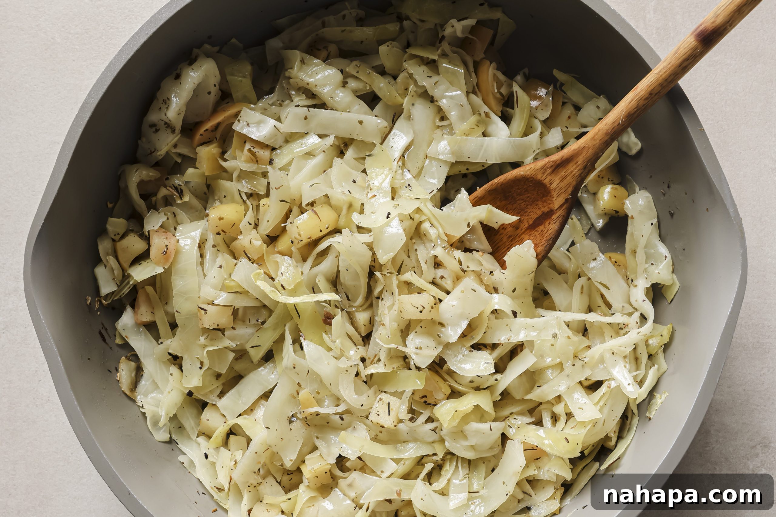 Diced apples and shredded cabbage gently sautéing in a pan, starting to soften and mingle their flavors.