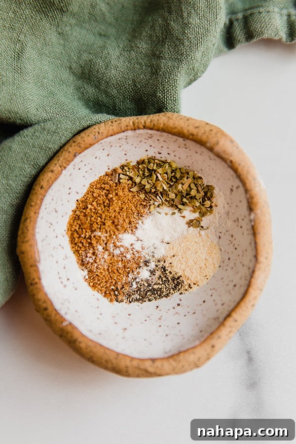 A small white bowl filled with a homemade spice blend, featuring various powdered spices and herbs, ready to season the pork chops.