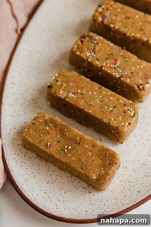 Several homemade cake batter protein bars, perfectly chilled and set, arranged on a serving platter, ready to be enjoyed as a healthy and vibrant snack.