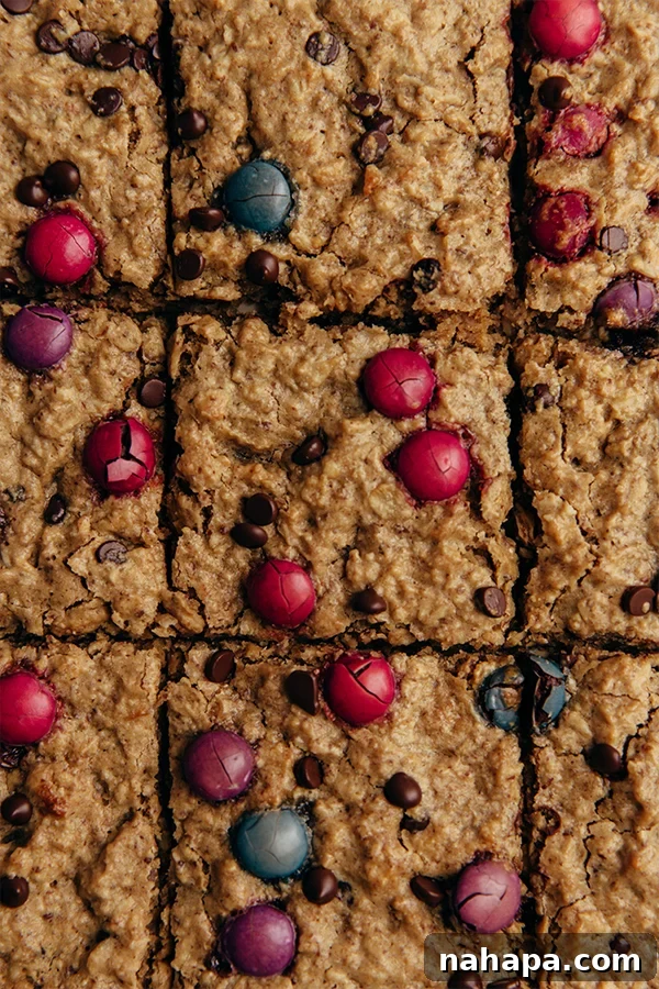 Up close image of oatmeal breakfast bars cut in squares, showing colorful candy gems and chocolate chips