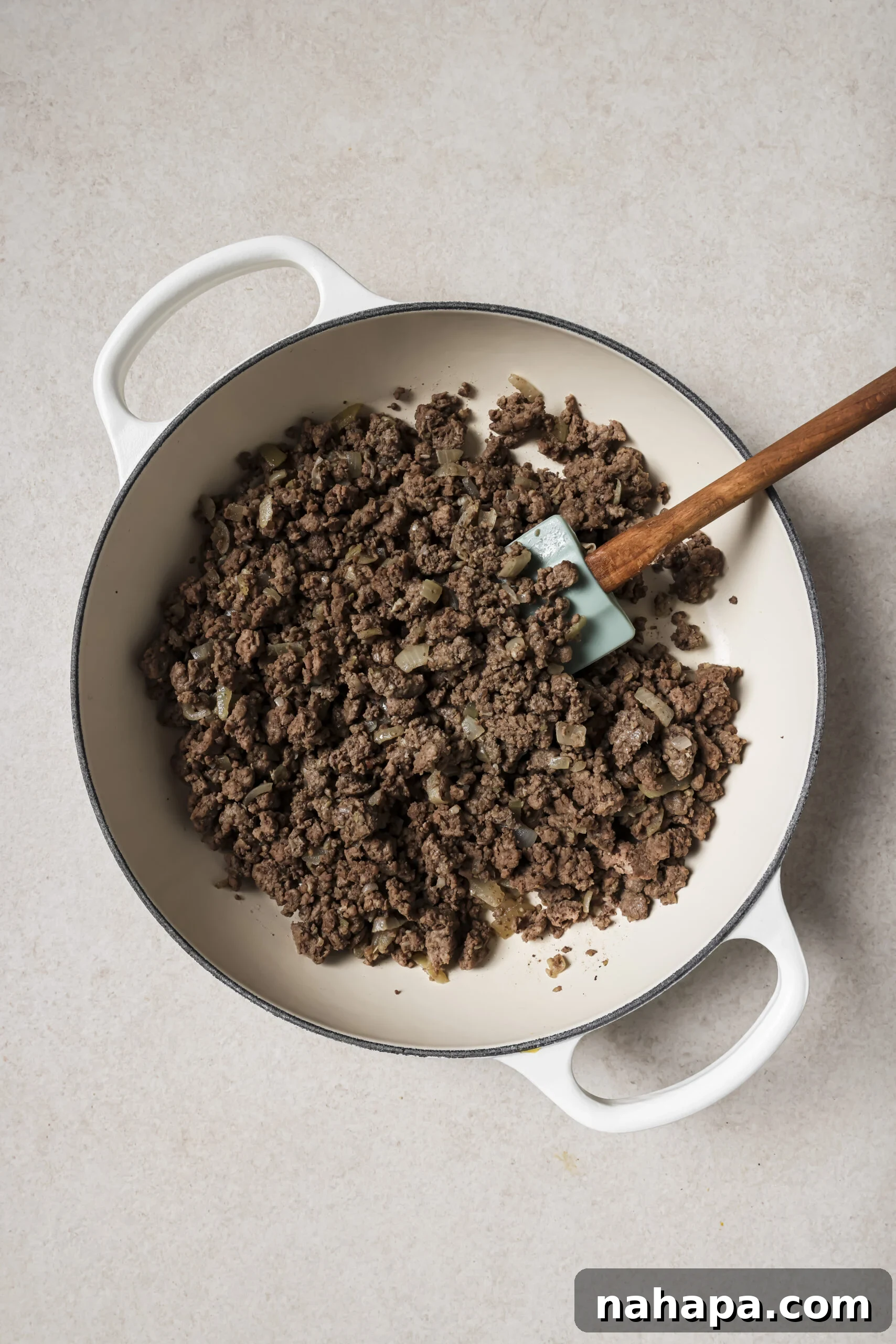 A large white pan with cooked ground beef.