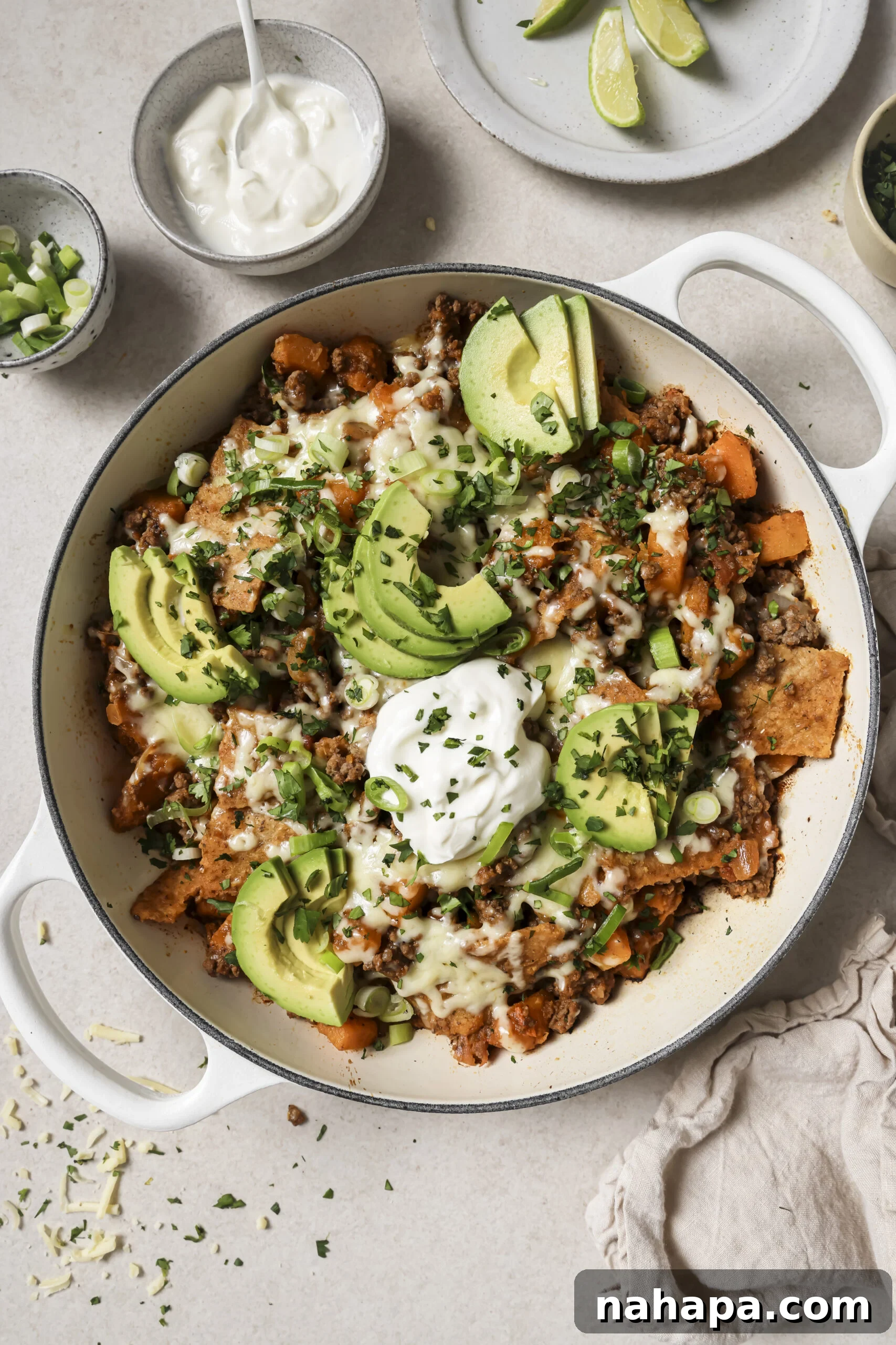 Enchilada skillet topped with avocado and chopped cilantro in a white pot.