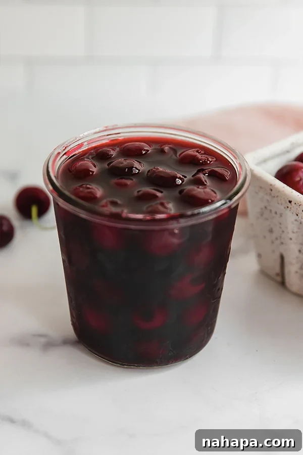 A close-up of homemade maraschino cherries in a glass jar, ready to be enjoyed as a garnish or snack.