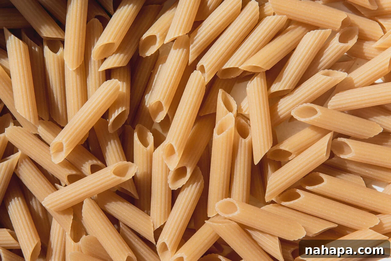 Uncooked gluten-free pasta spread evenly in a greased baking dish.