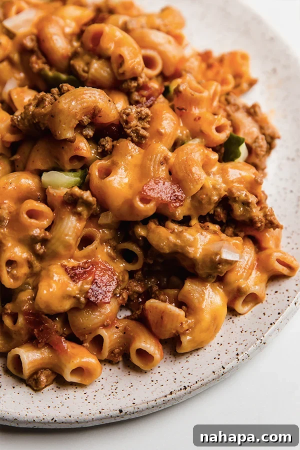 Ultimate No Boil Gluten Free Bacon Cheeseburger Pasta Bake 4 A portion of Bacon Cheeseburger No-Boil Pasta Bake with toppings on a plate, ready to be eaten.