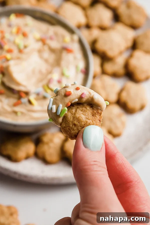 A Dunkaroo cookie with icing and sprinkles being lifted by a hand.