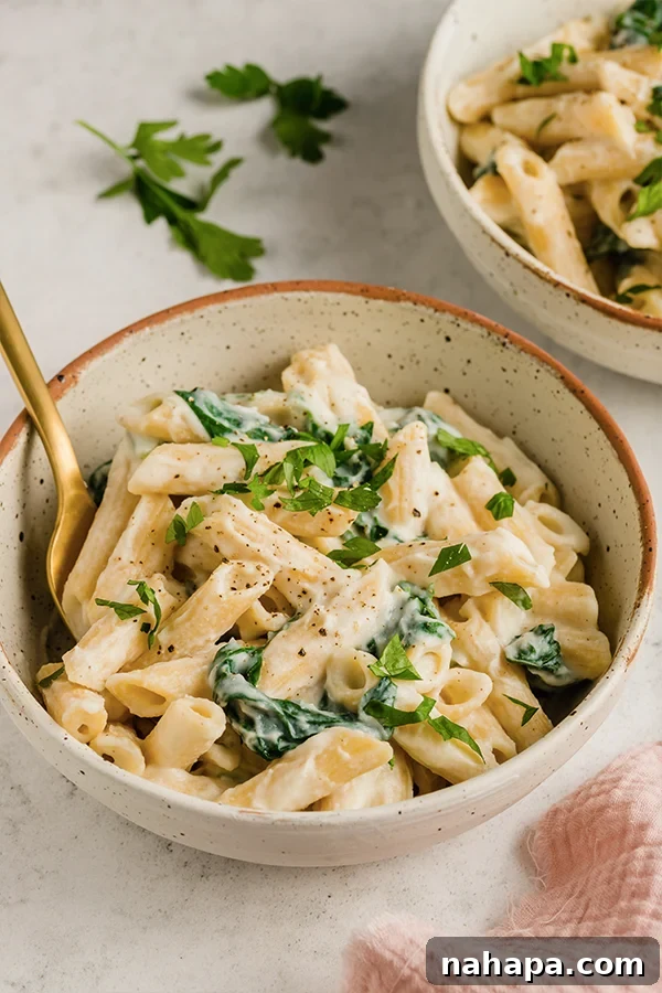 A bowl of Easy Penne Alfredo with chopped parsley on top. 