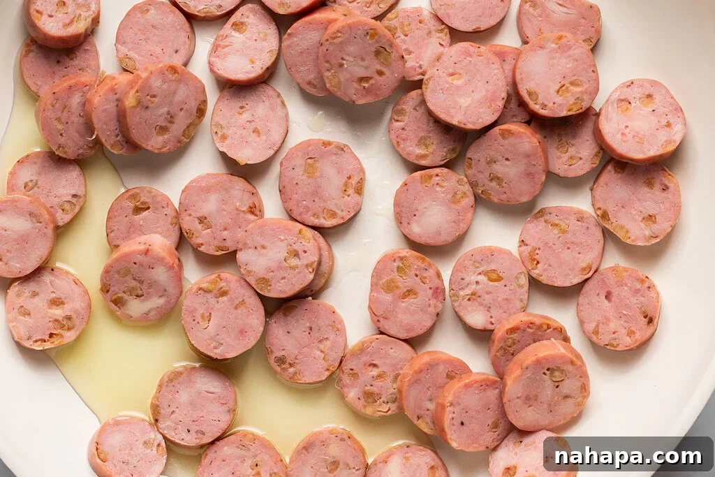 Sliced chicken apple sausage cooking in a hot skillet, browning evenly.