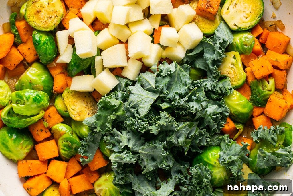 Sautéed sweet potato, Brussels sprouts, and onion browning in a skillet, showing a delicious caramelization.