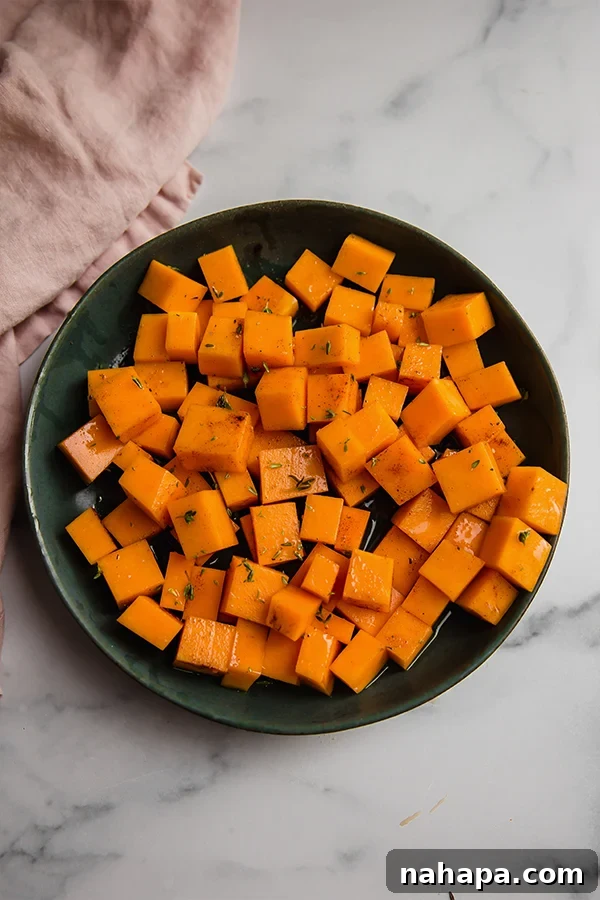 Freshly cubed butternut squash pieces gathered in a rustic wooden bowl, ready for seasoning.