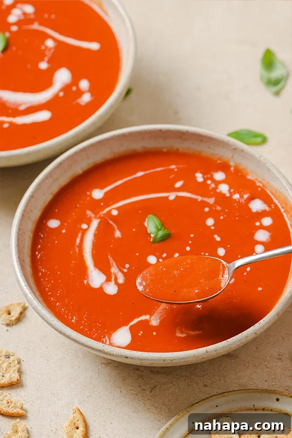 A bowl of nightshade-free tomato soup on a rustic wooden table, with fresh basil nearby.