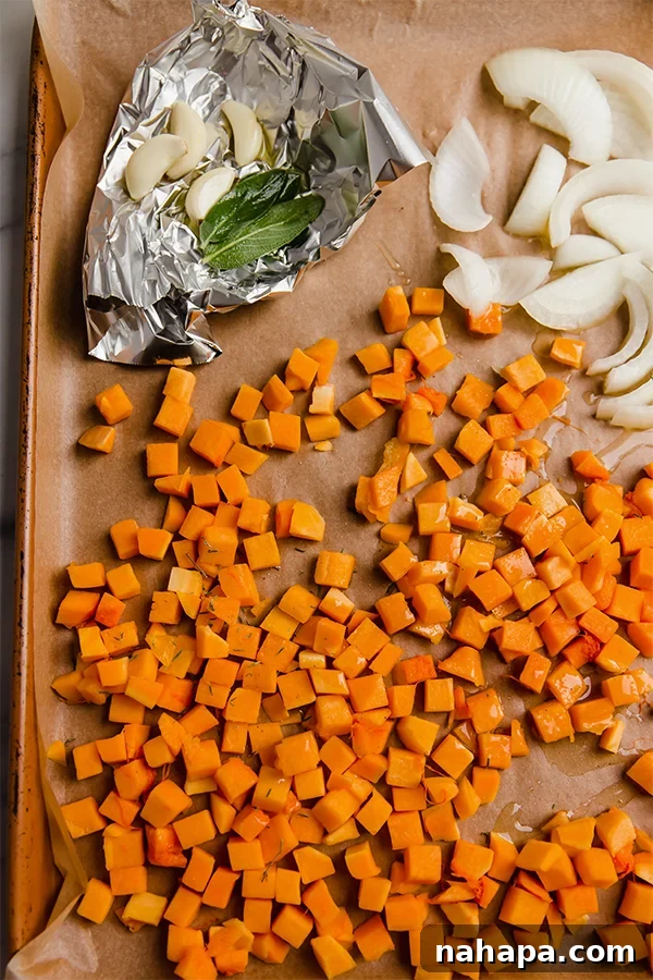 A sheet pan with sliced onion, garlic, and butternut squash.