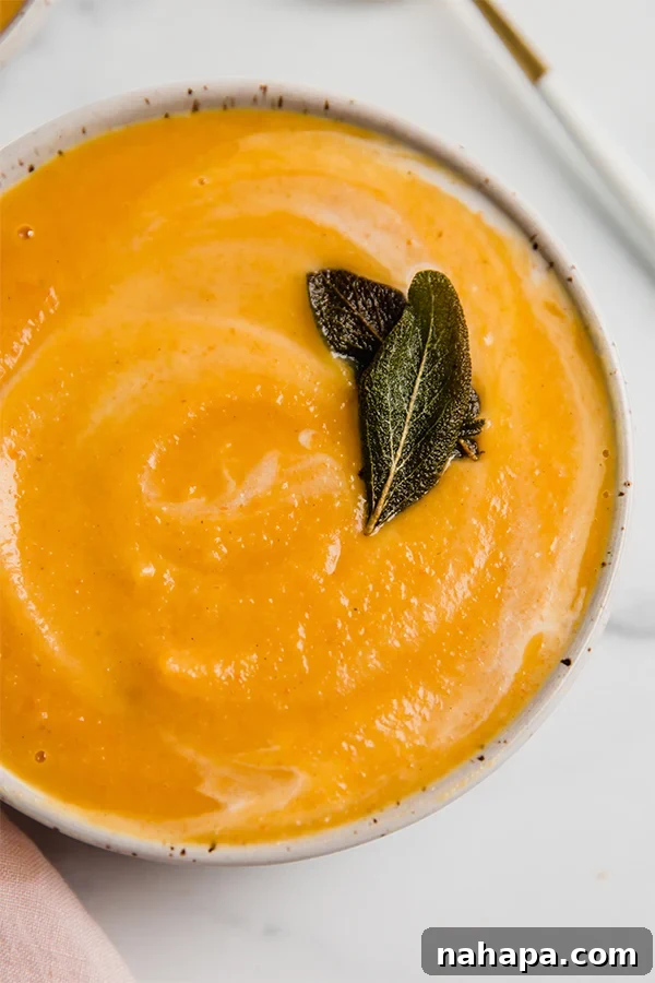 A beautifully garnished bowl of creamy roasted acorn squash soup, ready to be enjoyed.