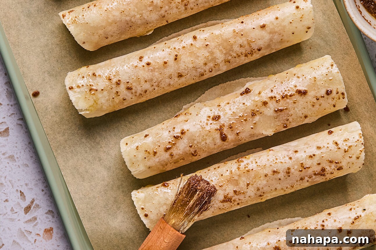 Apple Cinnamon Swirls Gluten Free 10 Apple pie roll ups rolled on a baking sheet and brushed with ghee and coconut sugar.