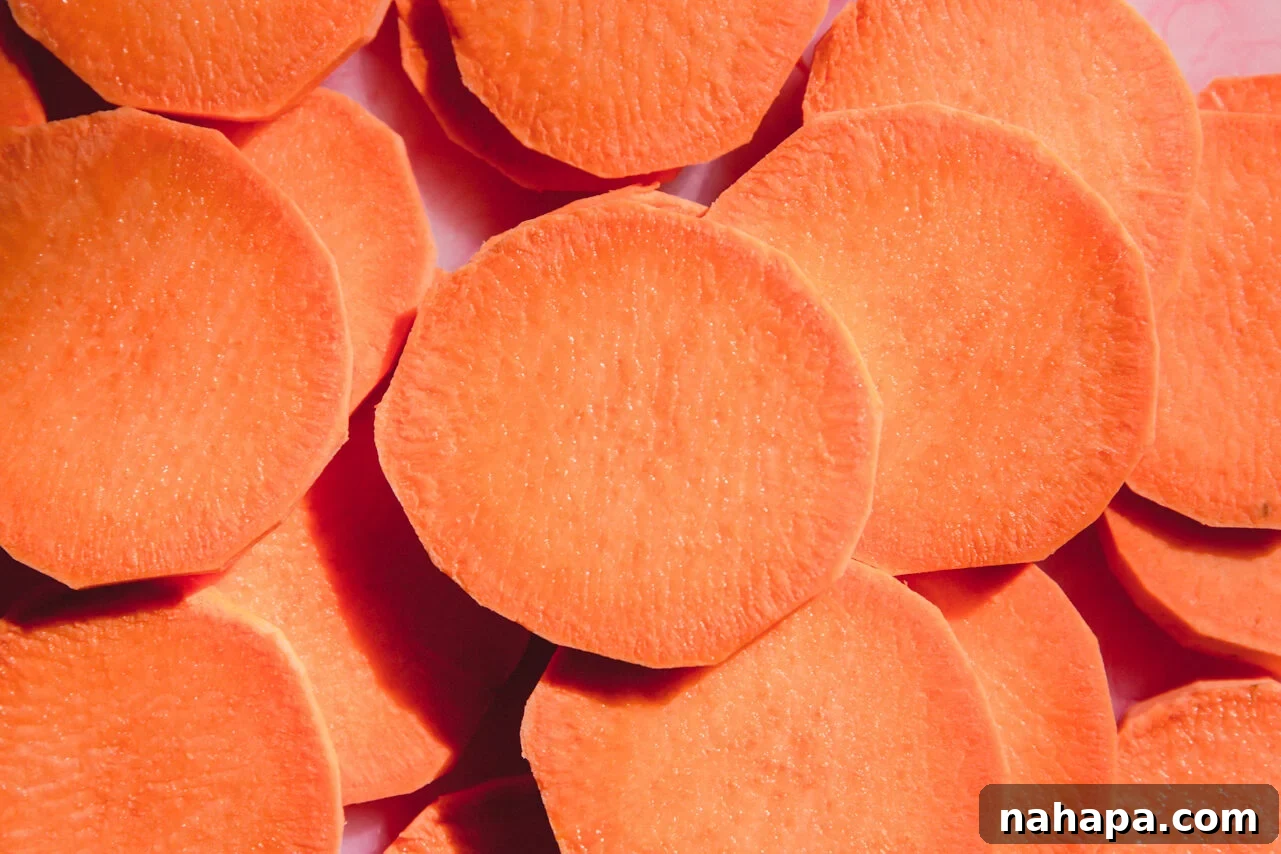 Sliced sweet potato rounds on a cutting board, ready for seasoning and baking.