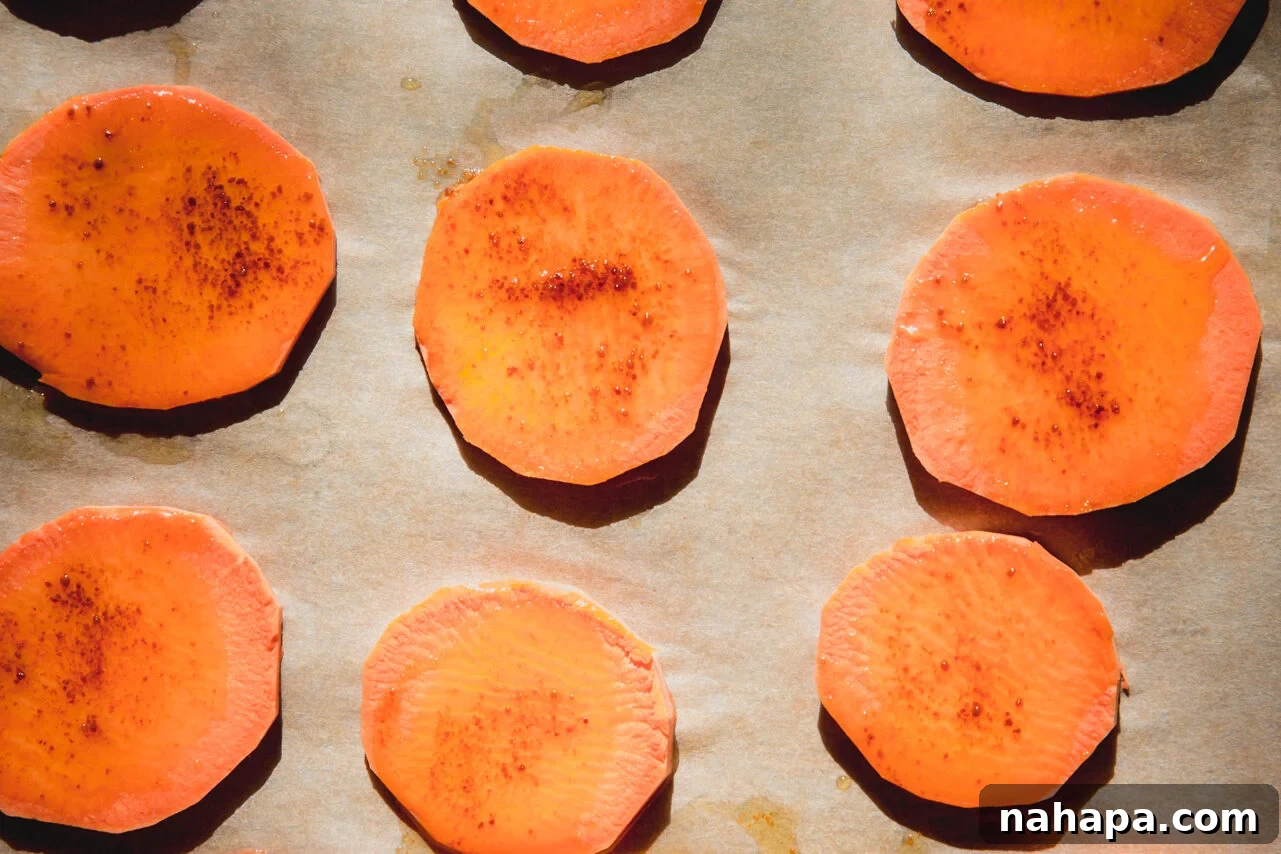 Mini sweet potato slices coated with ghee and coconut sugar, arranged on a baking sheet.