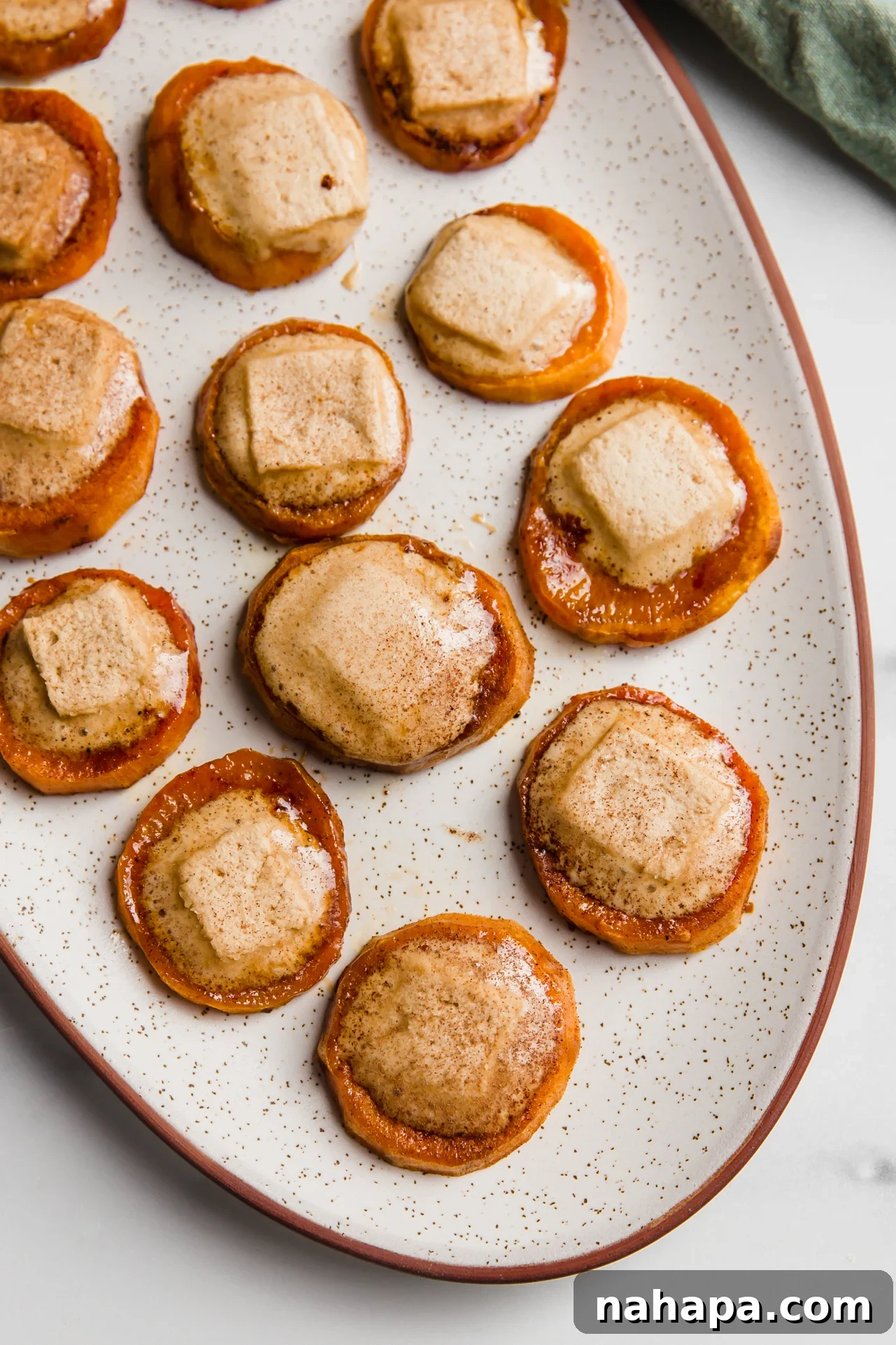 Sweet potato casserole bites with melted marshmallows arranged artfully on a large platter, ready for a holiday spread.