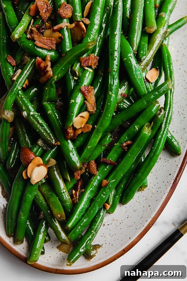 A close-up of the green beans with bacon and toasted almonds, highlighting the textures and vibrant colors.