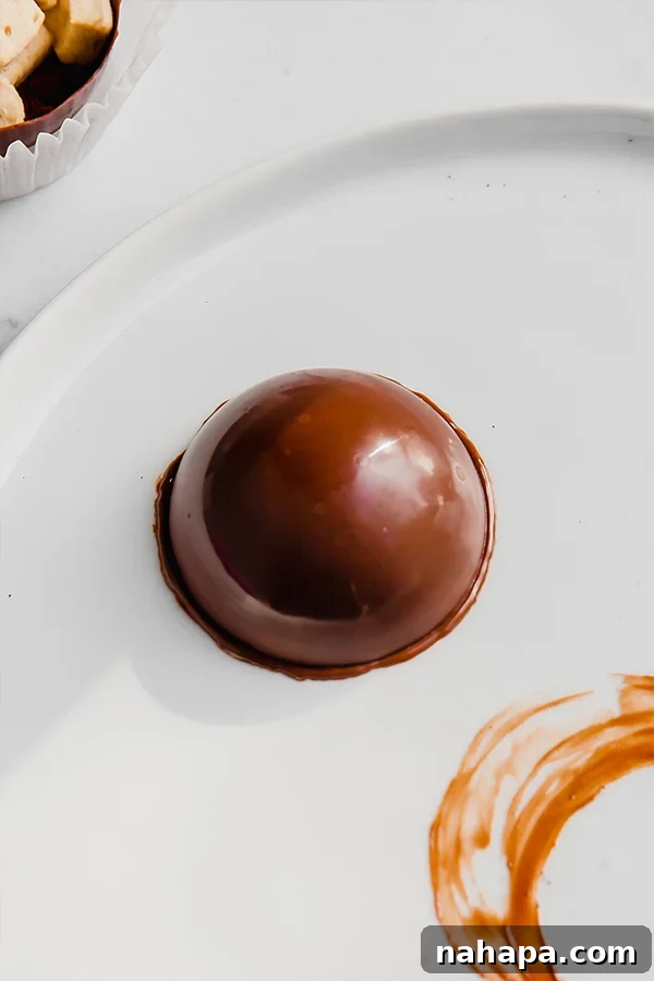 An empty chocolate shell melting its edge on a warm plate to prepare for sealing