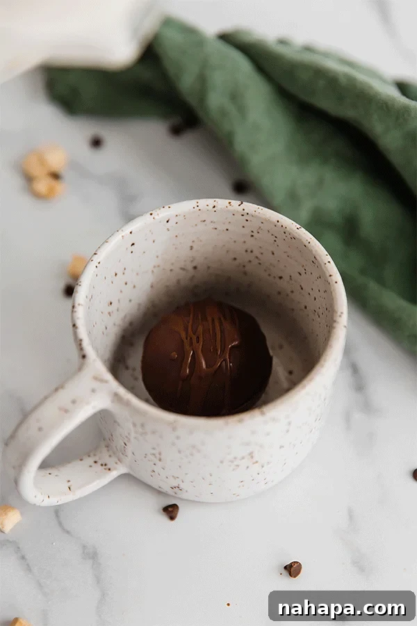 Animated GIF showing a hot cocoa bomb melting in hot milk, releasing marshmallows and cocoa mix