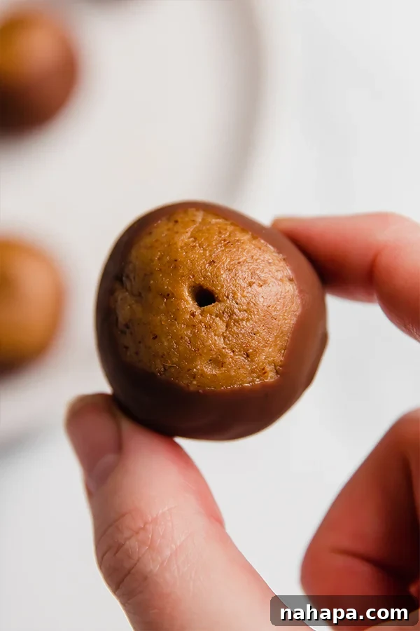 Paleo Buckeye Bites 4 Freshly dipped Paleo Buckeyes with a perfect chocolate coating and visible almond butter top, arranged on parchment paper