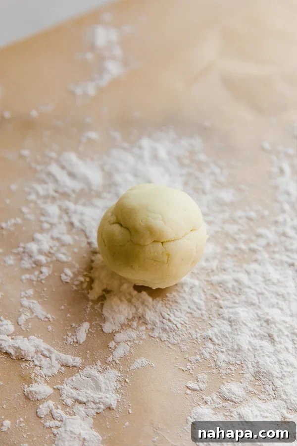Paleo AIP Sweet Potato Lefse: A Healthy Norwegian Delight 4 A small, perfectly smooth ball of sweet potato lefse dough resting on a lightly floured surface, prepared for rolling.