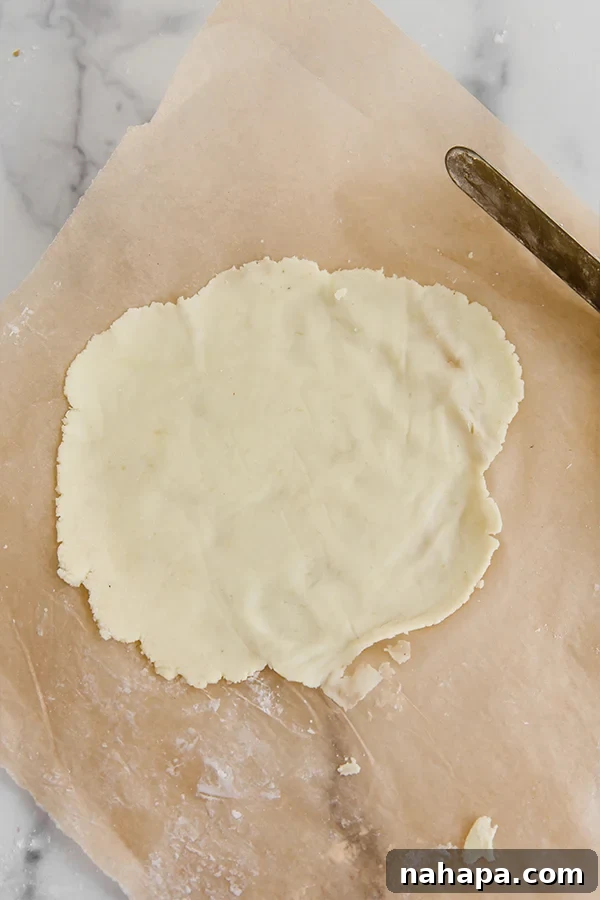 Paleo AIP Sweet Potato Lefse: A Healthy Norwegian Delight 5 Sweet potato lefse dough rolled out thinly between two sheets of parchment paper, demonstrating its delicate, almost transparent quality.