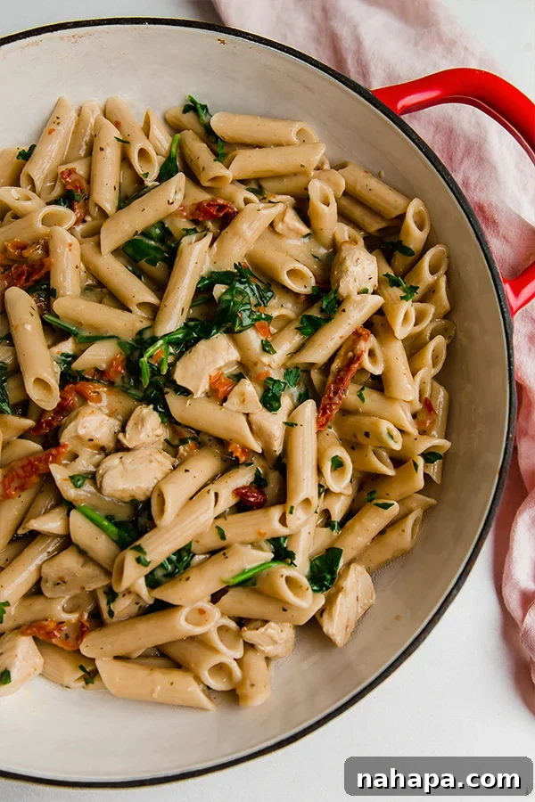 A large Dutch oven filled with creamy Tuscan chicken pasta, ready to be served.
