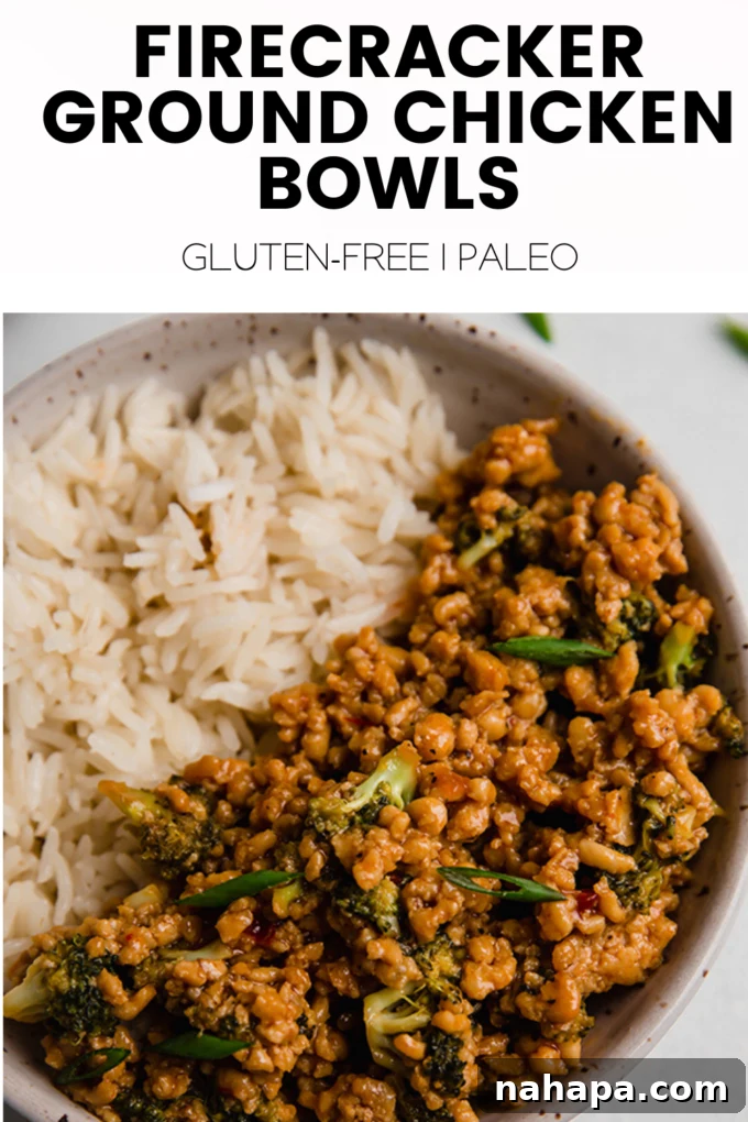 A beautifully arranged Firecracker Ground Chicken Bowl with rice and broccoli, ready for enjoyment. The bowl is placed on a rustic wooden surface with a spoon.