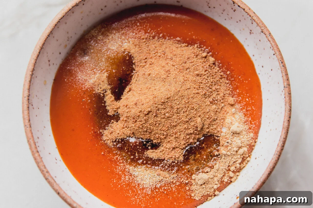 All the sauce ingredients including buffalo sauce, coconut aminos, coconut sugar, rice vinegar, ginger powder, and garlic powder, placed in a glass bowl unmixed, ready to be combined.