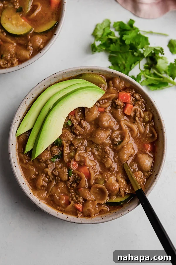 A delicious bowl of Conchitas con Carne topped with fresh sliced avocado.