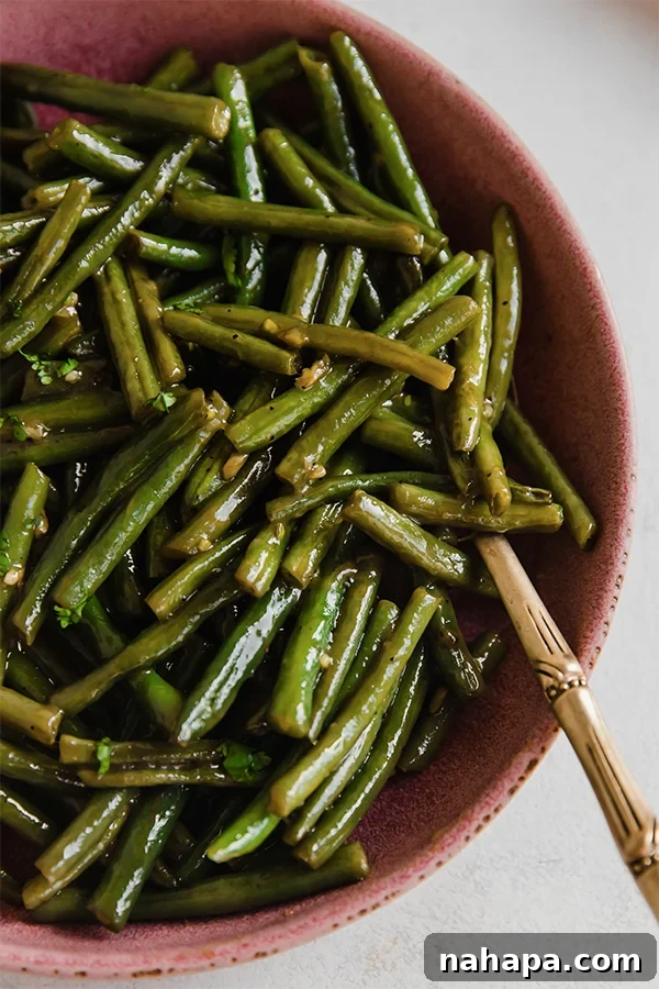 A vibrant bowl of sweet and sour Hungarian green beans, garnished with fresh parsley, ready to serve.