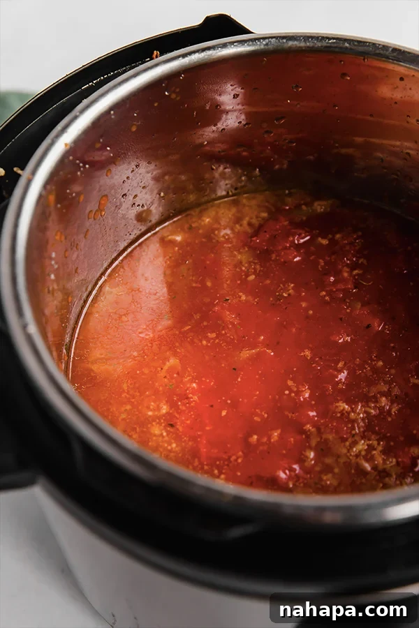 An instapot filled with sauce, pasta, and meat before cooking.