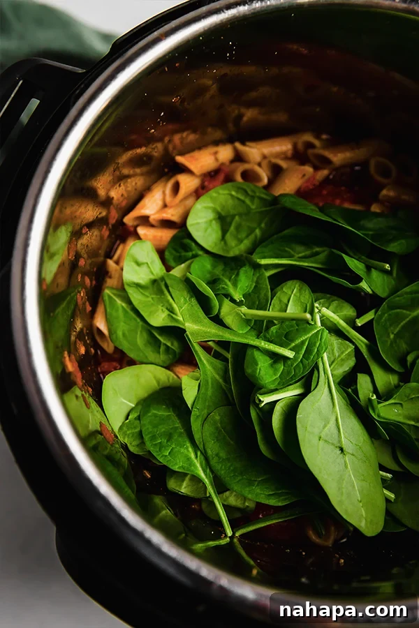 Spinach added on pasta in the Instant Pot, beginning to wilt.
