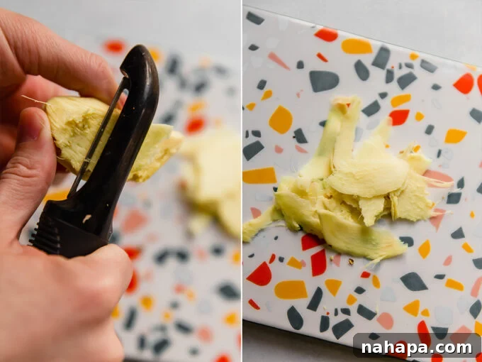 A close-up shot of hands peeling fresh ginger root with a spoon, demonstrating a simple and effective method.