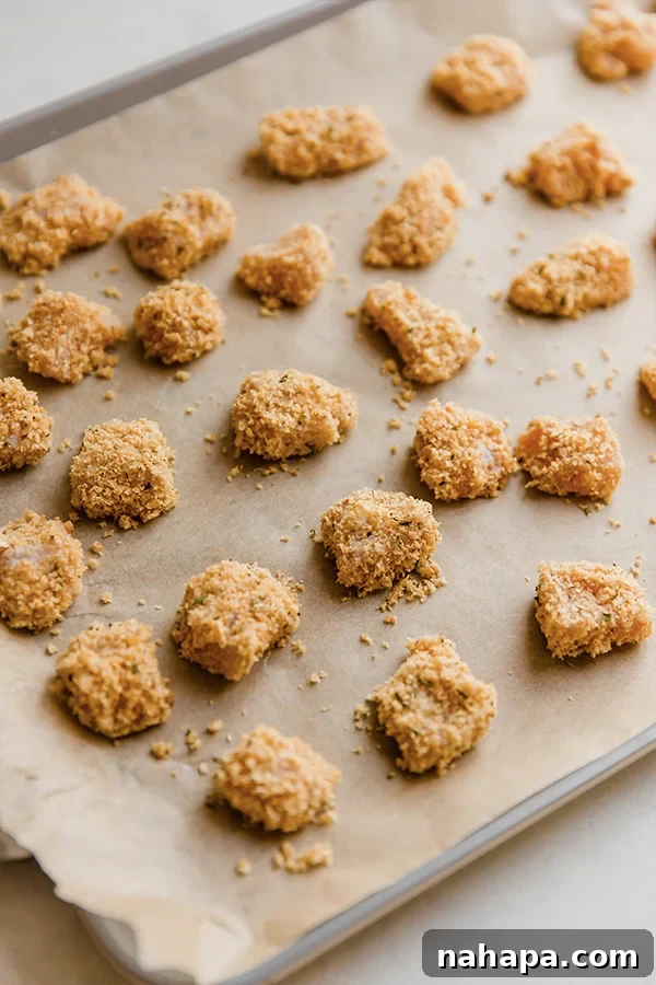 Pork panko chicken nuggets arranged on a parchment-lined baking sheet, ready for the oven.