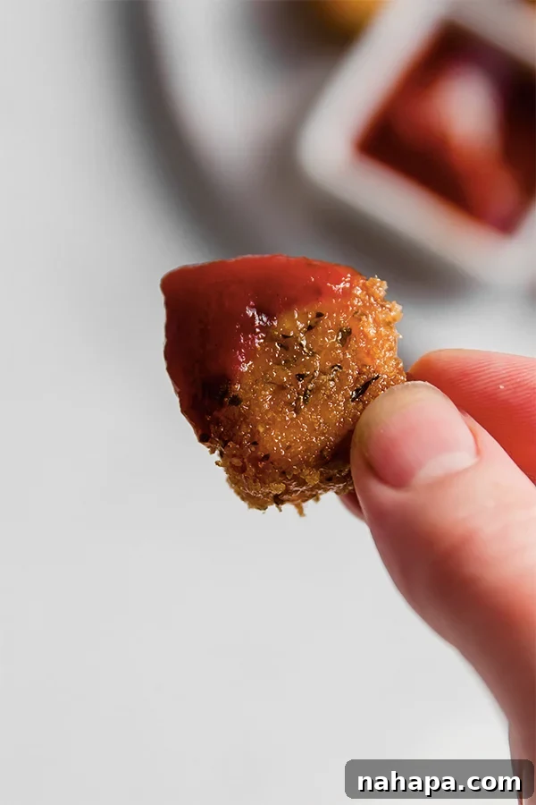 A single pork panko chicken nugget placed on a small plate next to a dipping sauce.