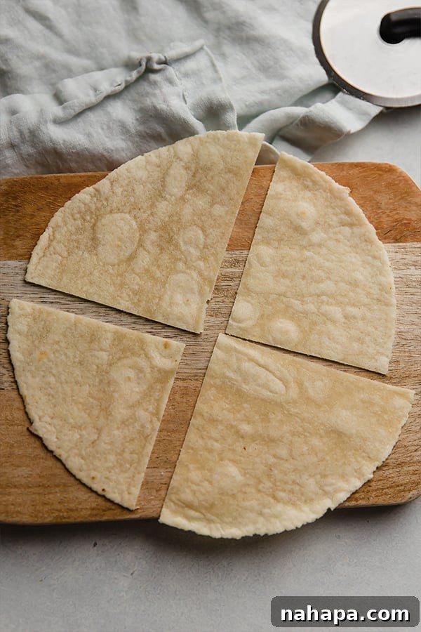 A close-up view of an almond flour tortilla that has been neatly sliced into four large triangular pieces using a pizza cutter, ready for the next step in the air frying process.