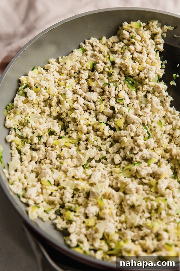 Wholesome Paleo Gluten-Free Ground Turkey Avocado Taquitos 4 A skillet filled with cooked ground turkey and shredded zucchini, seasoned and ready for taquito assembly.
