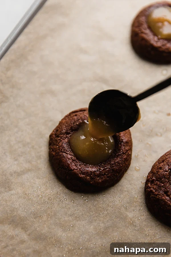 Adventureful Inspired Gluten Free Caramel Brownie Cookies 5 Filling the brownie cookies with homemade caramel on a baking sheet.
