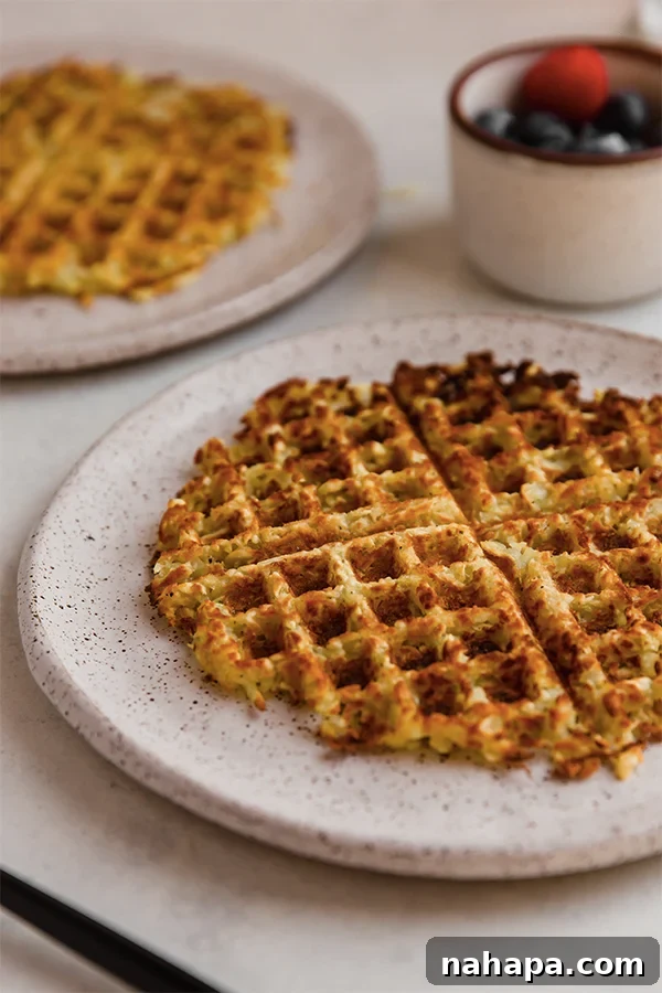 A freshly cooked, crispy sweet potato hashbrown waffle presented on a plate, showcasing its golden color.