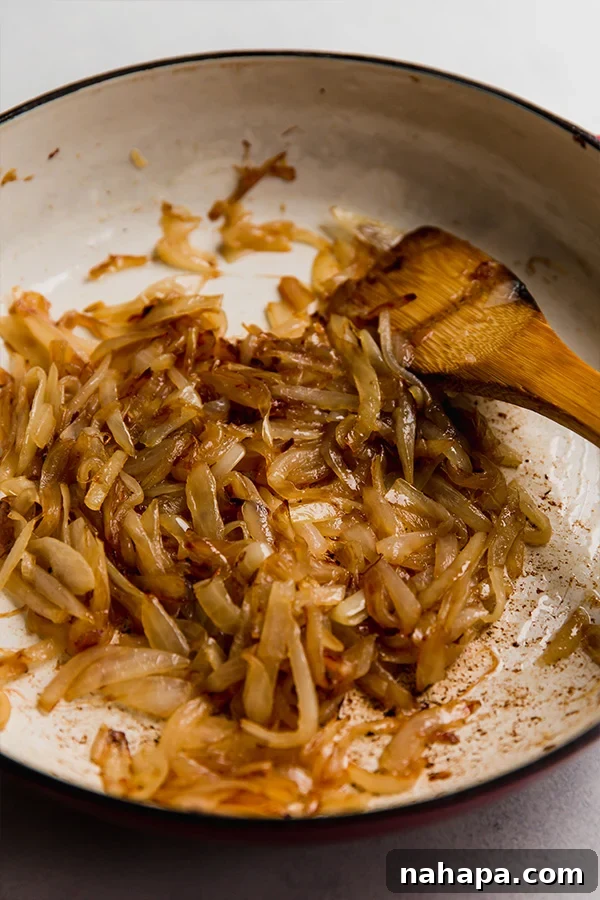 Caramelized onions in a pan, deep golden brown and tender.