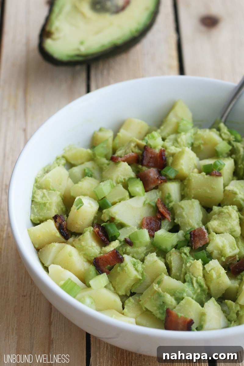 Close-up of AIP Avocado "Potato" Salad, showing a rich, green hue and visible bacon pieces.